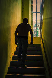 Rear view of man walking on staircase