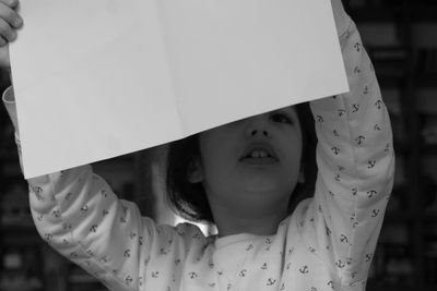 Close-up of girl holding blank paper while looking away