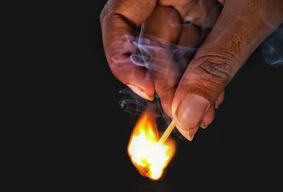 Close-up of hand holding fire against black background