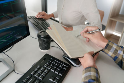 Midsection of programmers working on table