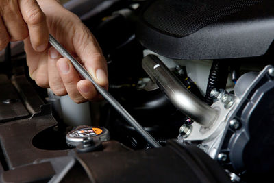 Cropped hand of mechanic repairing car engine with wrench