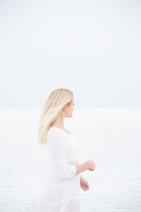 Woman standing in sea against clear sky