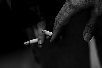 Cropped hand of people holding cigarettes