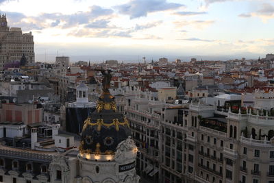 Panoramic view of statue amidst buildings in city against sky