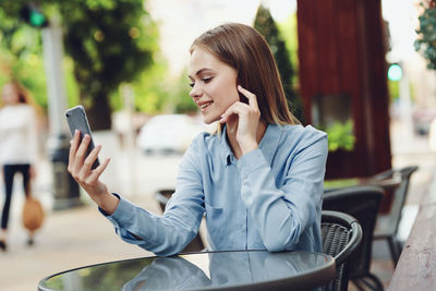 Young woman using mobile phone while sitting in cafe