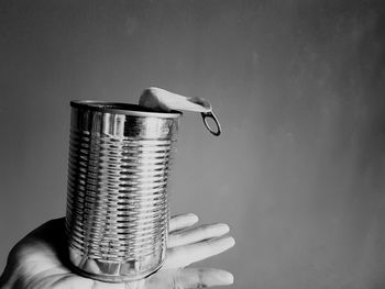 Close-up of hand holding tin can against wall