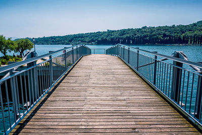 Wooden footbridge over water against sky