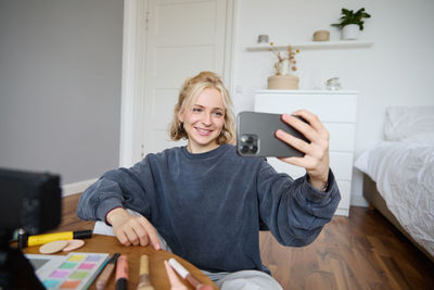 Young woman using phone while sitting at home