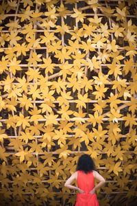 Rear view of woman standing against yellow wall