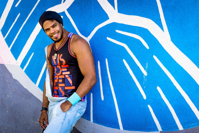 Portrait of smiling young man standing against blue wall