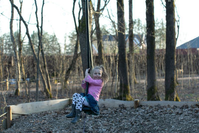 Rear view of woman sitting on rock in forest