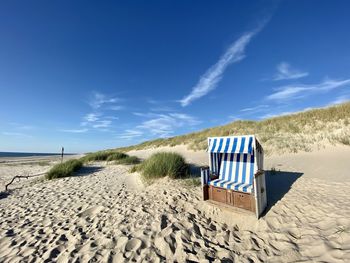 Lifeguard hut on beach against blue sky