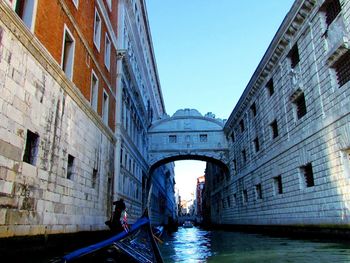 Bridge over canal amidst buildings against clear sky