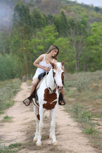 Full length of woman riding horse on land