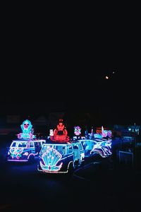 Illuminated ferris wheel against sky at night
