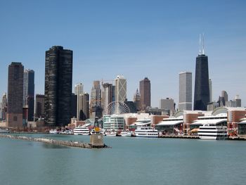 Modern skyscrapers by lake michigan in city against clear blue sky
