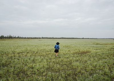 Rear view of woman walking on grassy landscape