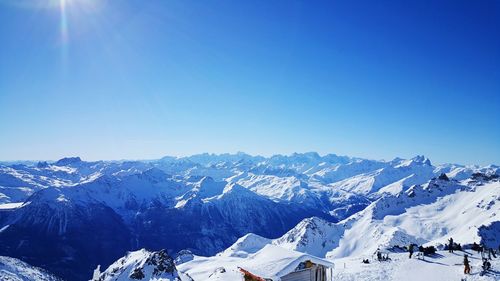 Scenic view of snow covered mountains against blue sky