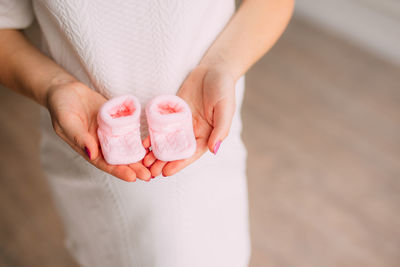 Woman holding baby booties at home