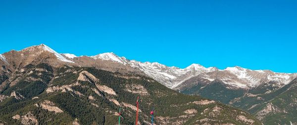 Low angle view of snowcapped mountains against clear blue sky