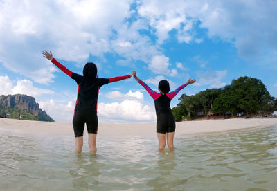Rear view of woman with arms outstretched standing on water
