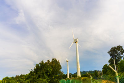 Low angle view of wind turbines against sky