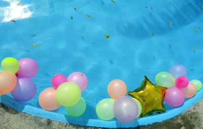 Multi colored balloons in water against blue sky