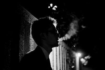 Side view of man smoking at night