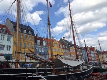 Boats moored at harbor against cloudy sky