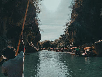 People on river amidst trees against sky