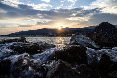 Rocks in sea against sky during sunset