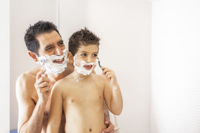 Funny father and son shaving in the bathroom