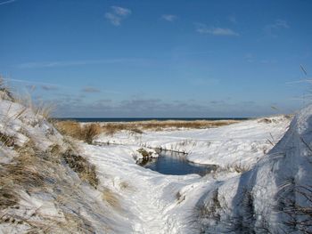 Scenic view of snow covered land against blue sky