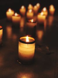 Close-up of lit tea light candles in darkroom