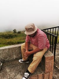 Full length of man sitting on grass against sky