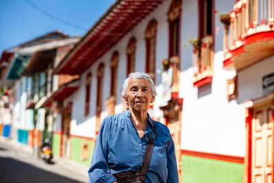 Portrait of young woman standing against building