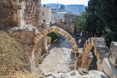 Arch bridge amidst buildings against trees