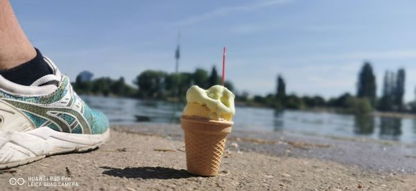 Low section of person with ice cream against sky