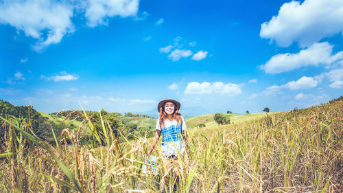 Rear view of woman standing on field against sky