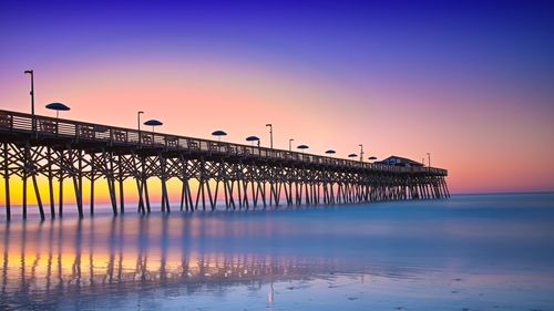 Pier over sea against sky during sunset