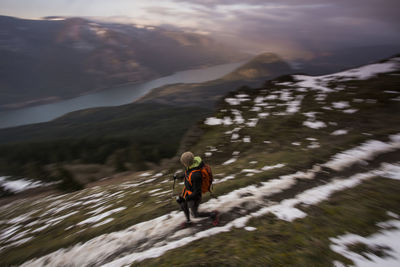 A young man climbs on dog mountain overlooking the columbia gorge.