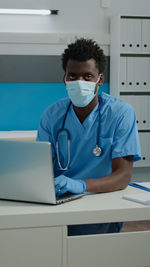 Doctor wearing mask using laptop in clinic