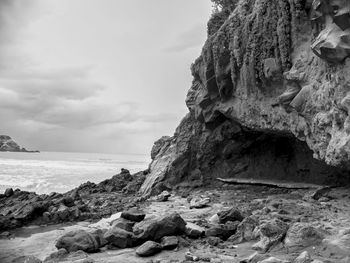 Rock formation on beach against sky