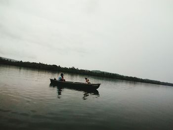 People in boat on lake against sky