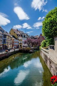 Bridge over river by buildings against sky