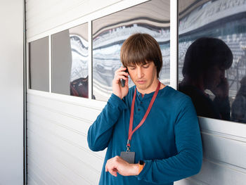 Man with badge talks by smartphone on pit lane at autodrom. sports car racing. sports competition