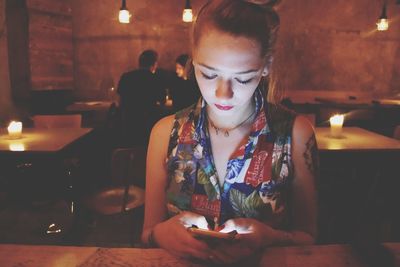 Young woman using smart phone in restaurant