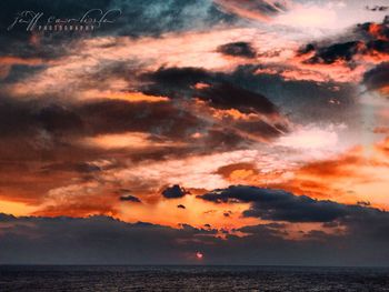 Scenic view of sea against dramatic sky during sunset