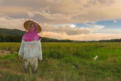 Man standing on field against sky during sunset