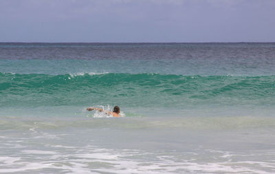 Man swimming in sea against sky